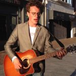 Owen Neid playing guitar on the street