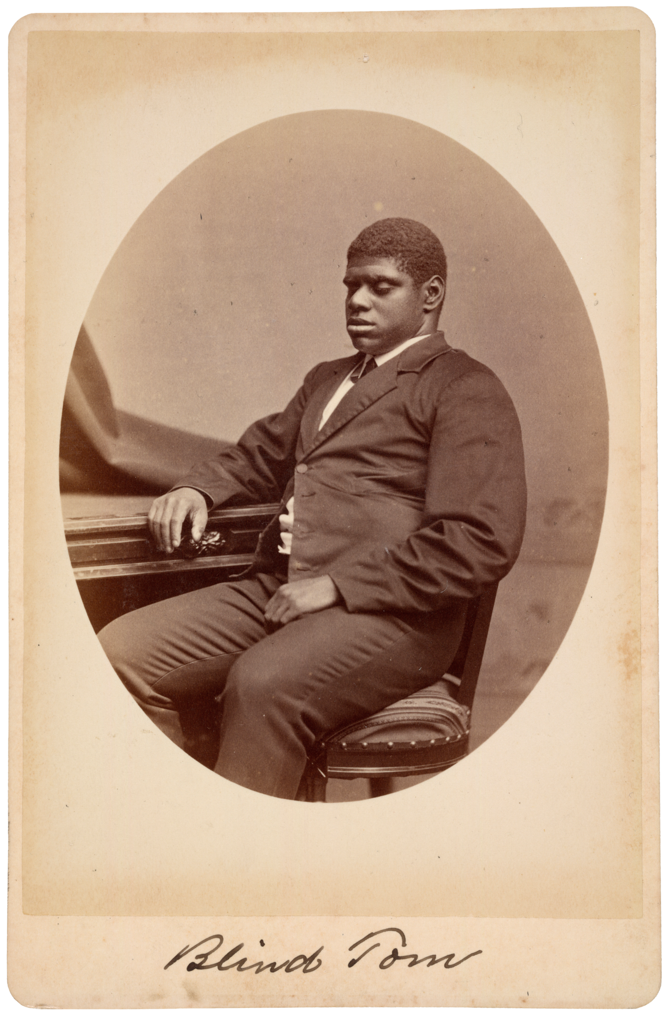 Thomas Wiggins seated beside a piano, with his full head and figure visible